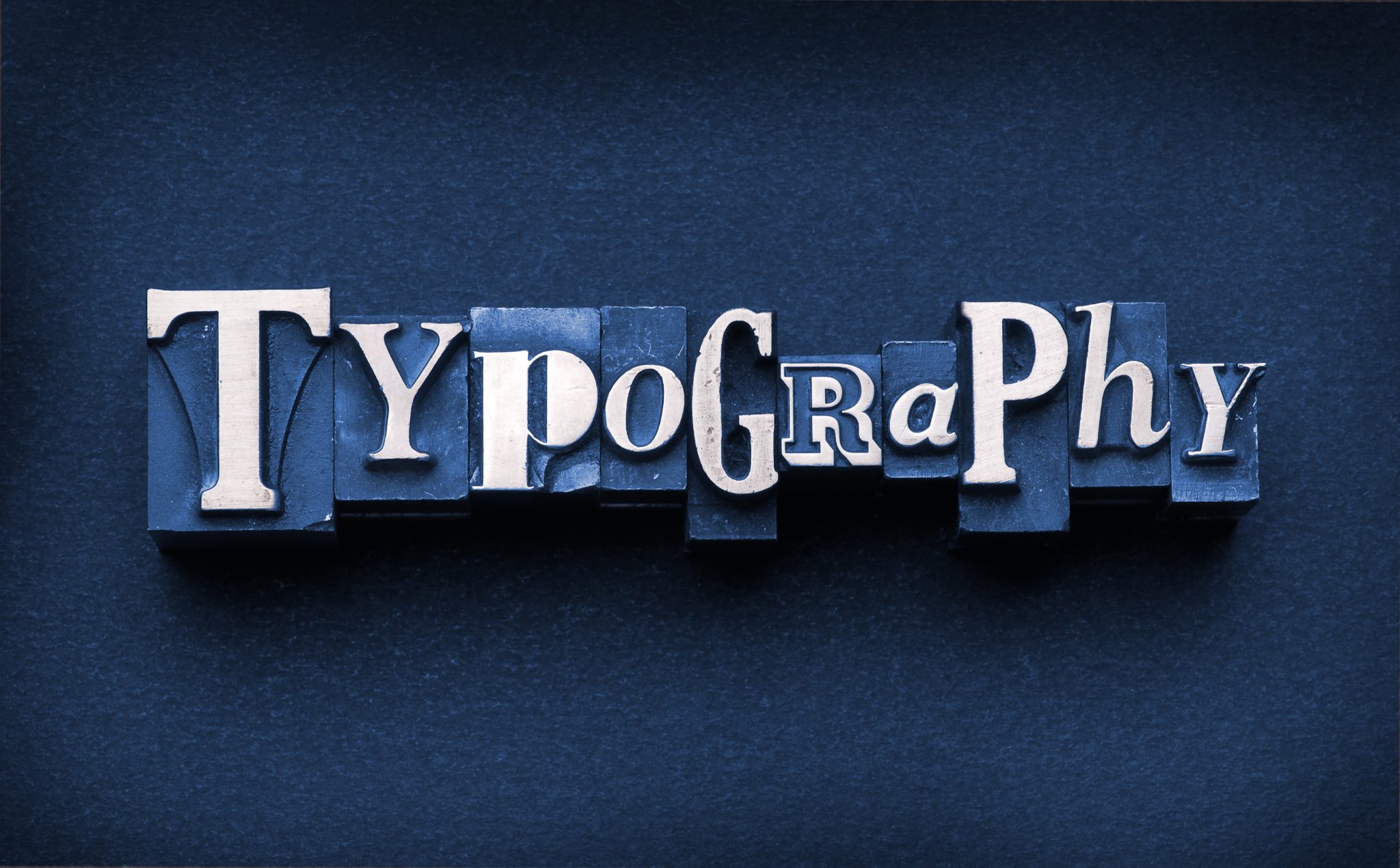 The word "Typography" done in letterpress type on a dark paper background and hand-tinted.